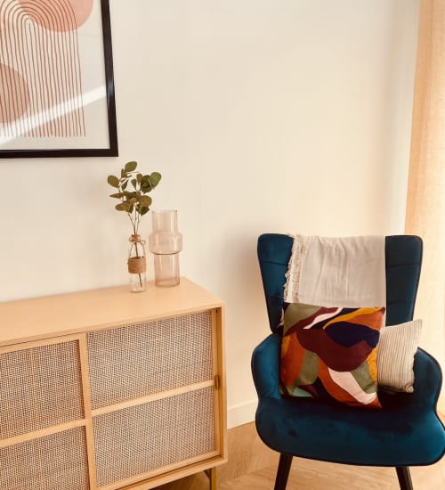 Le cabinet à Paris 20ᵉ : fauteuil bleu canard, plaid et buffet en cannage