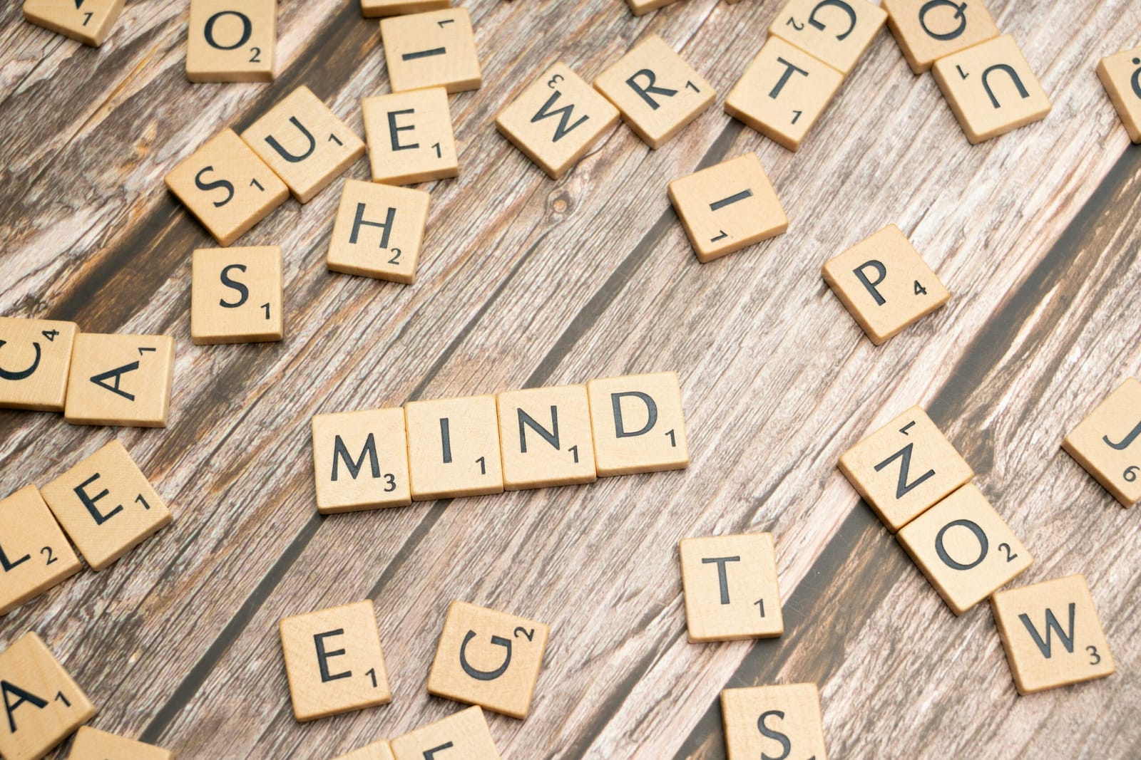 Des lettres de Scrabble formant le mot « mind » sur un plateau de bois