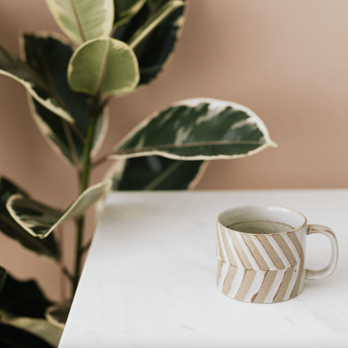 Une tasse de café sur un bureau et une plante